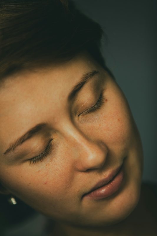 woman's face smiling, in peaceful gaze, eyes closed