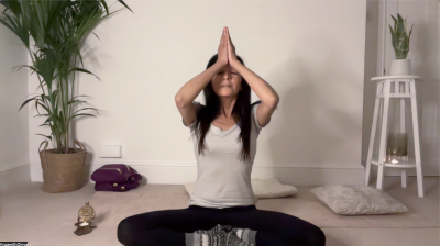 yoga teacher Divya Kohli in a lotus position yoga posture with hands in prayer at the third eye
